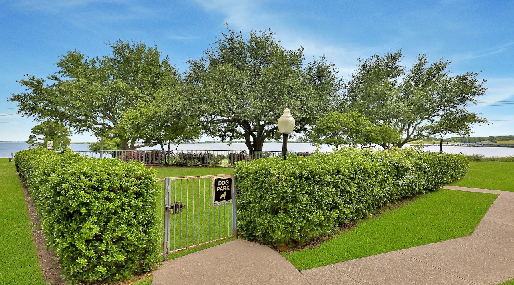a gated walkway with bushes and trees on either side of it